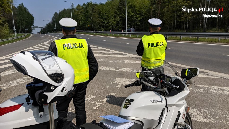 dwaj policjanci ruchu drogowego przy policyjnych motocyklach obserwują ruch pojazdó
